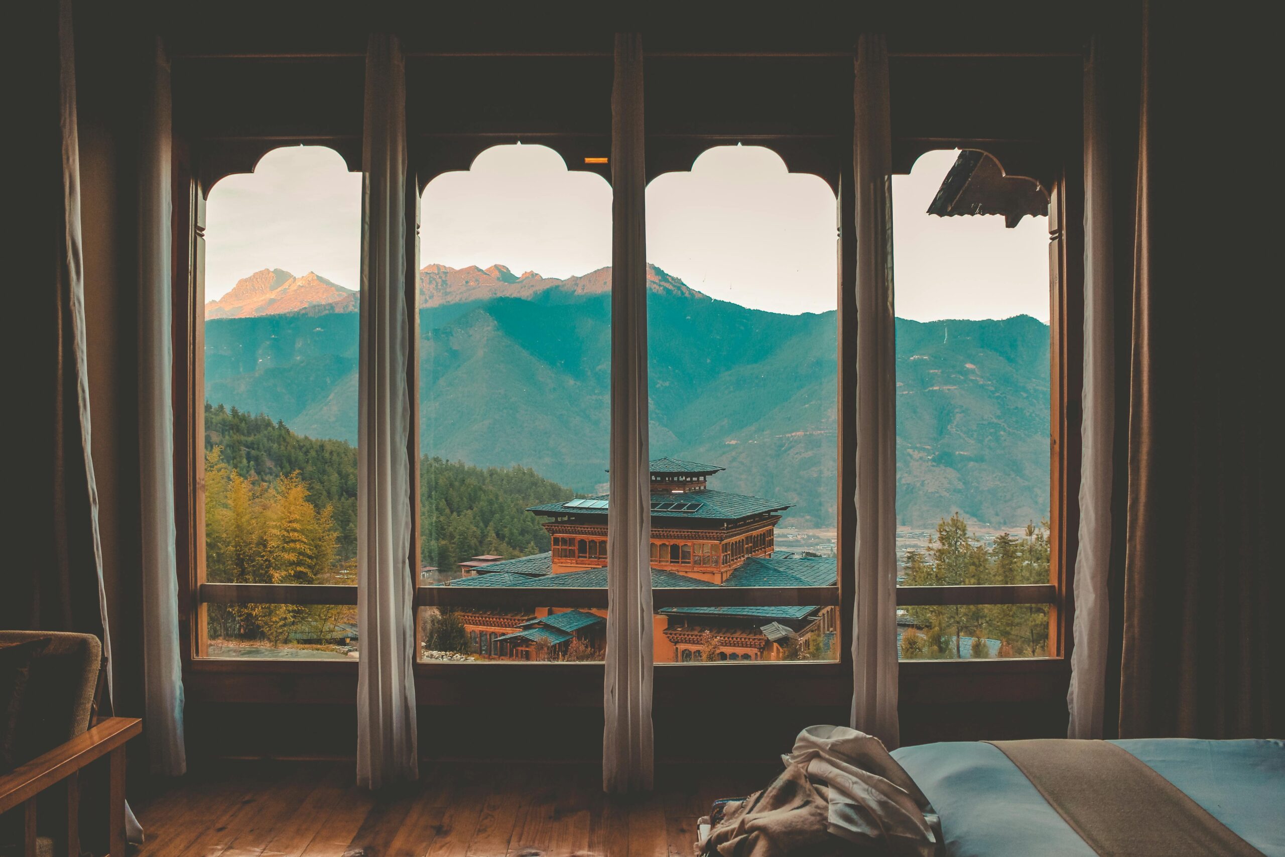 View of traditional Bhutanese architecture from an interior window, framed by mountains.